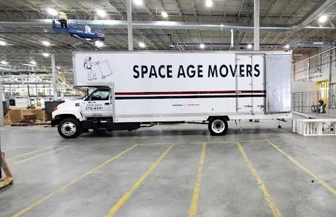 A large moving truck with the logo "SPACE AGE MOVERS" parked inside a warehouse, showcasing the company's focus on reliable moving services.